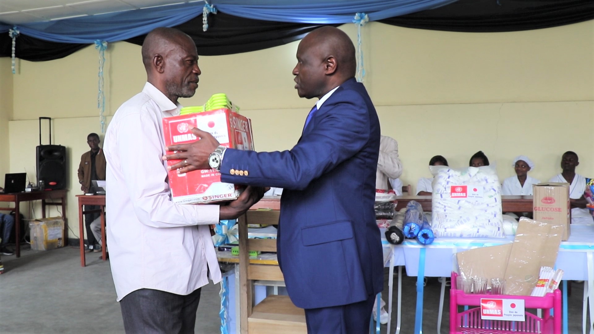 Un bénéficiaire recevant du représentant du Ministre provincial de la santé un kit de matériels de coupe et couture